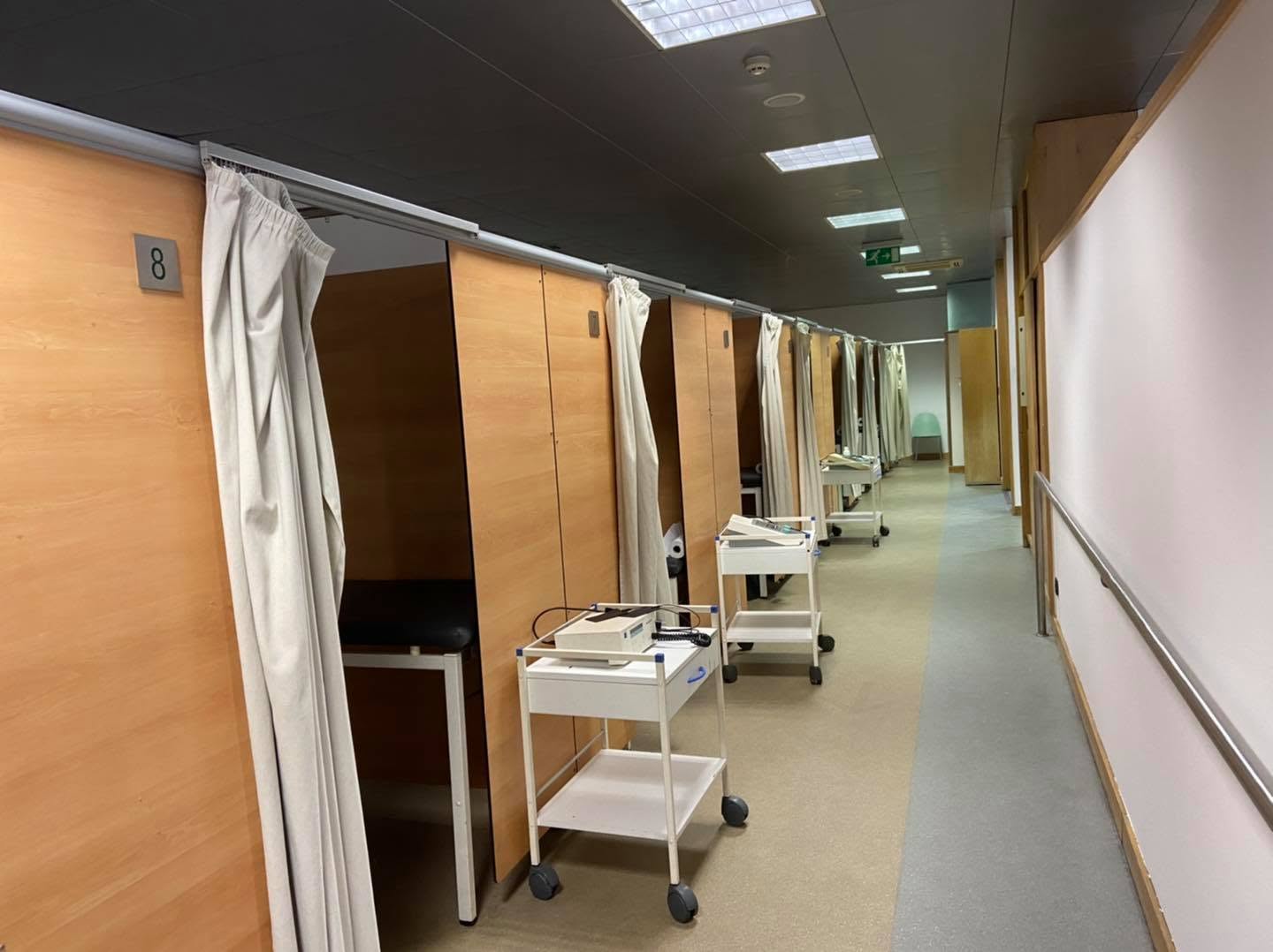 Corredor da Clínica Fisiátrica Calvário do Carvalhido, com gabinetes de tratamento equipados e macas de fisioterapia.